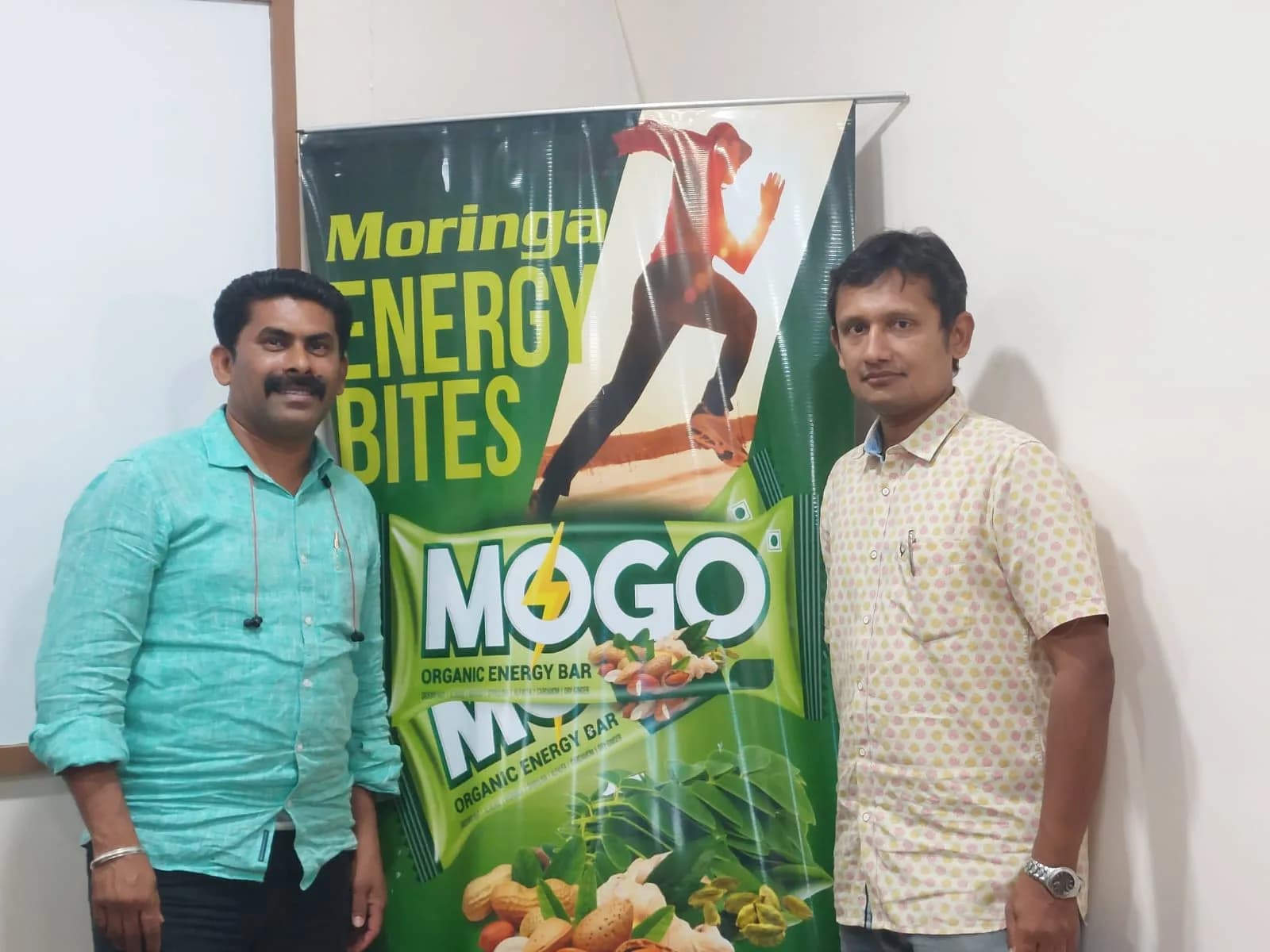 Two people beside a MOGO Moringa Energy Bites banner